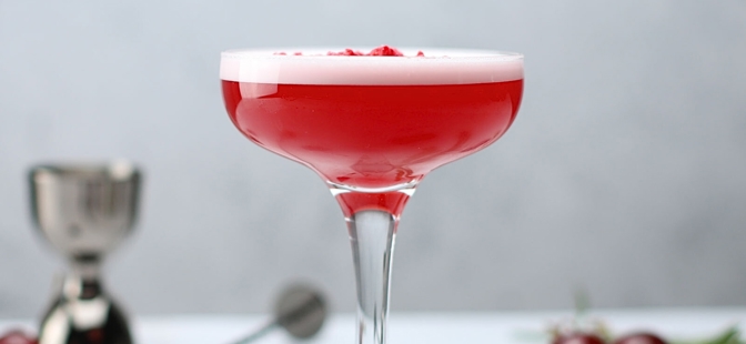 Coupe Glasses

An Essence Coupe Glass filled with a red cocktail and garnished with Frona Strawberry Powder on top. Along with some cherries that are dotted around the glass accompanied with rosemary, a measuring jigger and a twisted bar spoon.