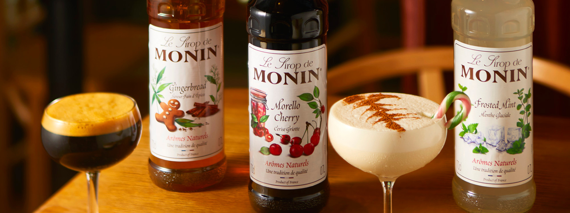 MONIN gingerbread and morello cherry syrup next to 2 foamy cocktails